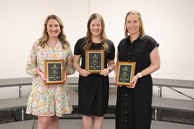 Three staff members stand with plaque