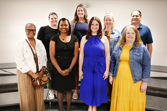 Staff members stand with awards for years of service