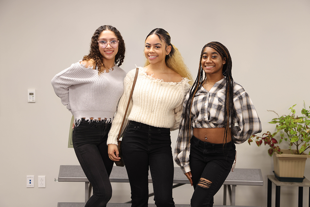 Three female students are shown standing next to each other at a recognition program.